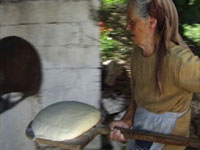 a woman putting bread dough into a brick oven to bake