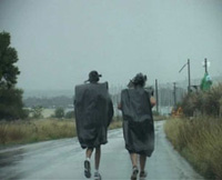 a still from the film: long distance runners wearing garbage bin liners to protect themselves from the rain